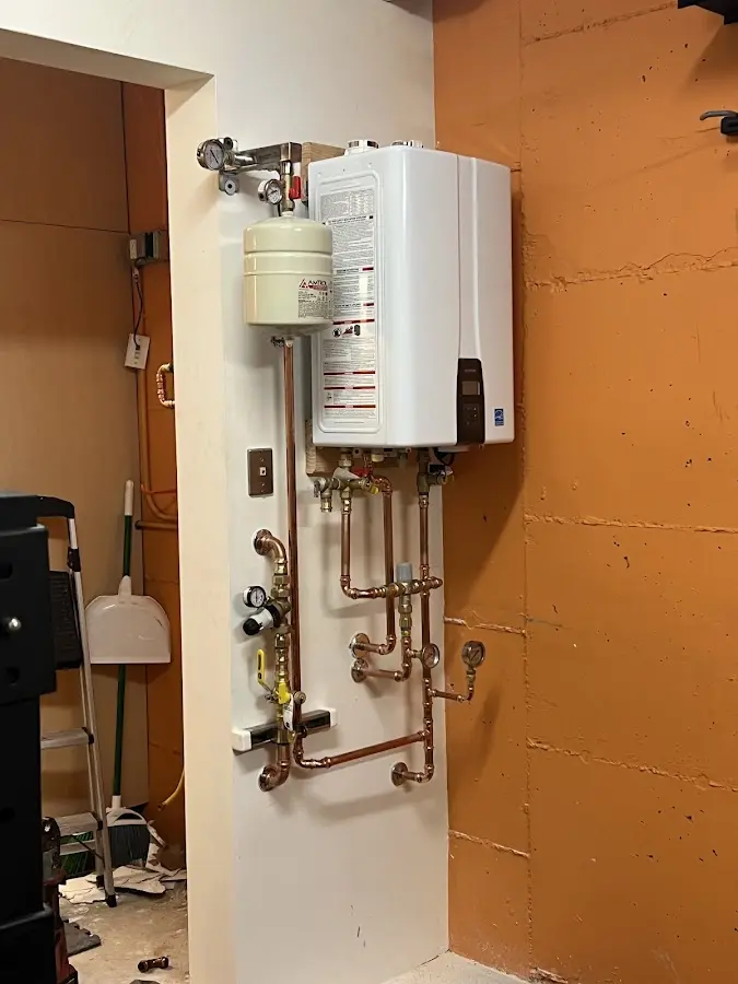 Plumbing technician inspecting water heater connections in Carver